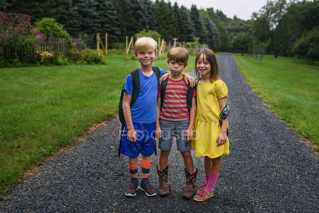 Retrato de tres niños de pie en un sendero, Estados Unidos - foto de stock