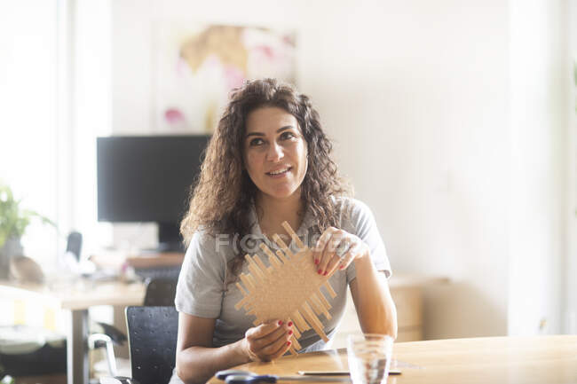 Улыбающаяся женщина сидит за столом и поднимает коробку с молоком — стоковое фото