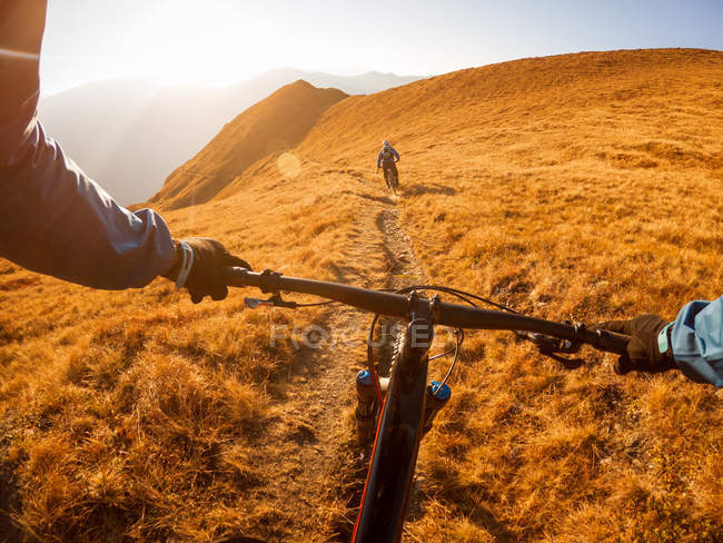 Personal perspective shot of a man mountain biking with a friend in the Alps, Gastein, Salzburg, Austria — Stock Photo