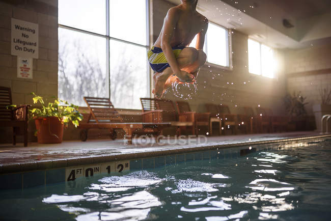 Garçon sautant dans une piscine — Photo de stock