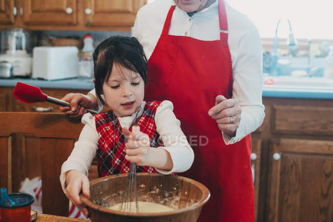Grand-mère enseignant à sa petite-fille à cuisiner — Photo de stock