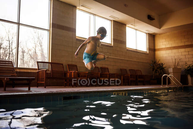 Chico saltando en una piscina - foto de stock