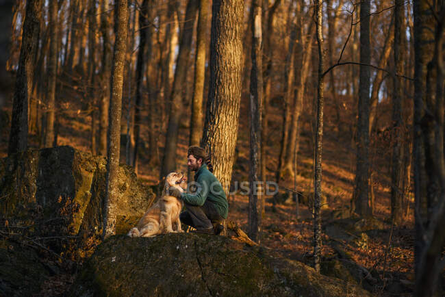 Uomo seduto nel bosco con il suo cane, Stati Uniti — Foto stock