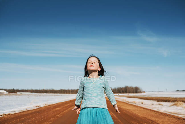 Retrato de una chica parada en la carretera con los ojos cerrados, Estados Unidos - foto de stock