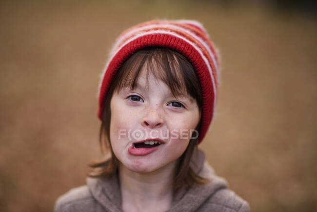 Retrato de una chica en un sombrero de lana tirando caras raras - foto de stock