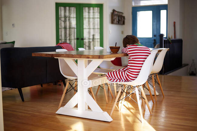 Boy sitting at a breakfast table sulking — Stock Photo