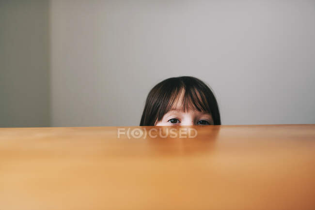 Девушка прячется за столом — стоковое фото
