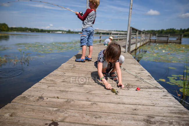 Três crianças pescando em uma doca no verão, Estados Unidos — Fotografia de Stock