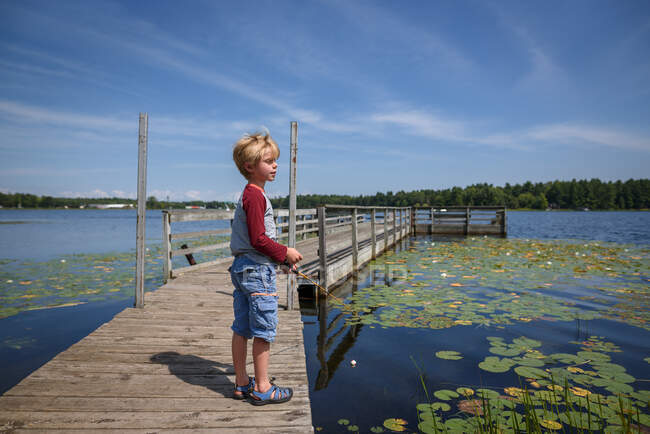 Niño de pie en un muelle de pesca, Estados Unidos - foto de stock