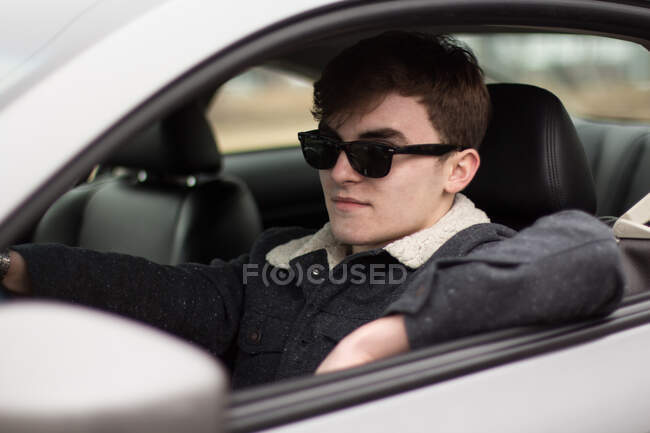 Hombre con gafas de sol conduciendo un coche - foto de stock
