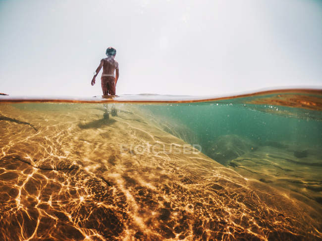 Niño de pie sobre una roca en el lago Superior, Estados Unidos - foto de stock