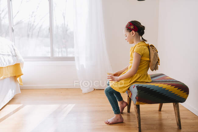 Porträt eines Mädchens, das auf einem Schemel sitzt und einen goldenen Gutschein hält — Stockfoto