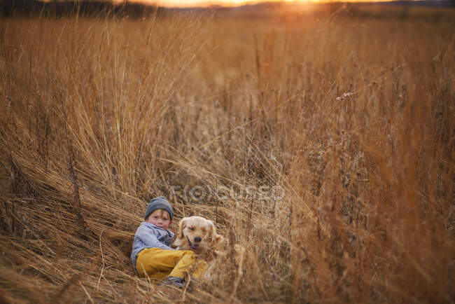 Ragazzo sdraiato in un campo con il suo cane golden retriever, Stati Uniti — Foto stock