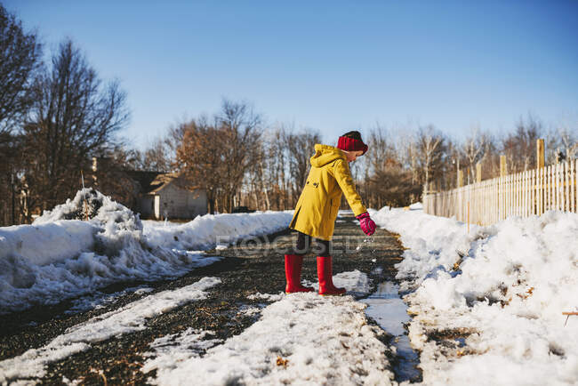 Ragazza che gioca vicino a una pozzanghera di neve che si scioglie, Stati Uniti — Foto stock