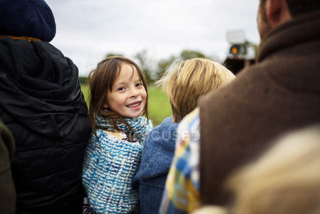 Lächelndes Mädchen, das mit seiner Familie im Waggon sitzt und ihr über die Schulter schaut — Stockfoto