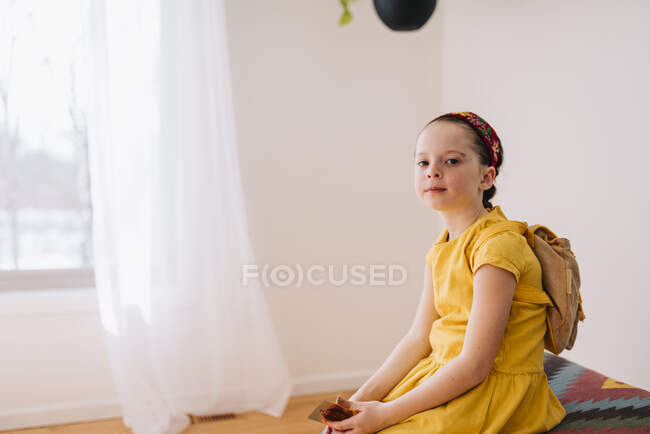 Retrato de uma menina sentada em um banquinho segurando um certificado de presente de ouro — Fotografia de Stock