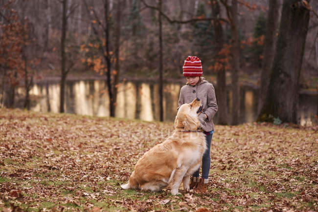 Chica de pie en el bosque jugando con su perro, Estados Unidos - foto de stock