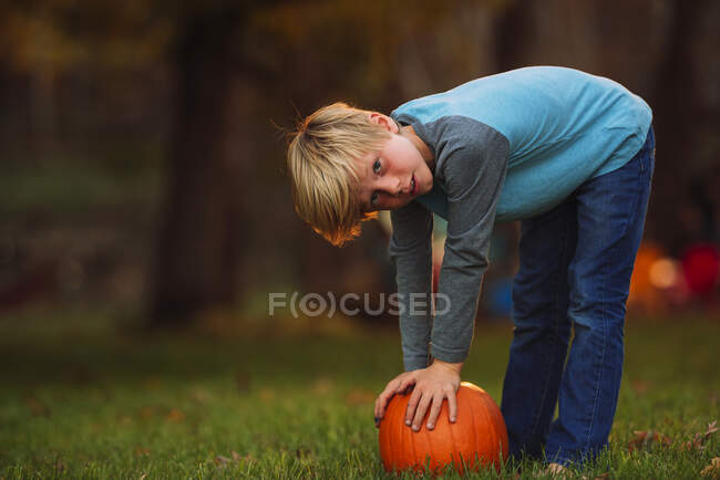 Menino em um jardim se curvando para pegar uma abóbora, Estados Unidos — Fotografia de Stock