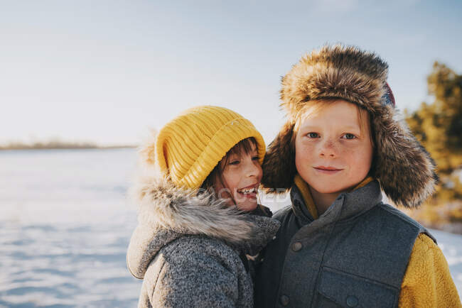 Retrato de un niño y una niña de pie junto a un lago, Estados Unidos - foto de stock