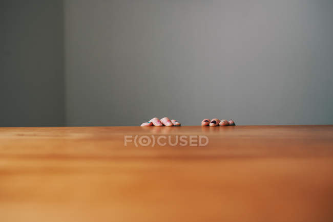 Fille mains tenant le bord d'une table — Photo de stock
