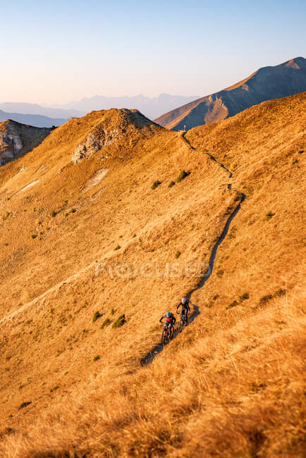 Homem e mulher de bicicleta de montanha nos Alpes Austríacos ao pôr-do-sol perto de Gastein, Salzburgo, Áustria — Fotografia de Stock