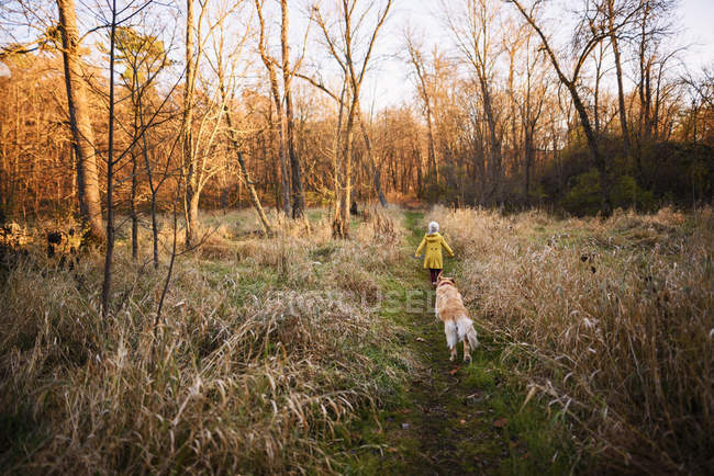 Дівчинка, яка гуляє в лісі зі своїм собакою, США. — стокове фото