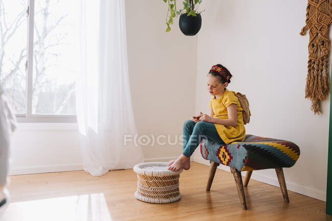 Fille assise sur un tabouret regardant un bon d'or — Photo de stock