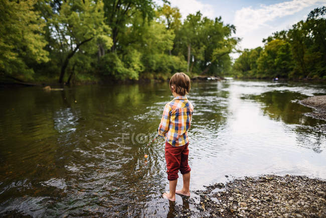 Мальчик, стоящий у реки на рыбалке, США — стоковое фото
