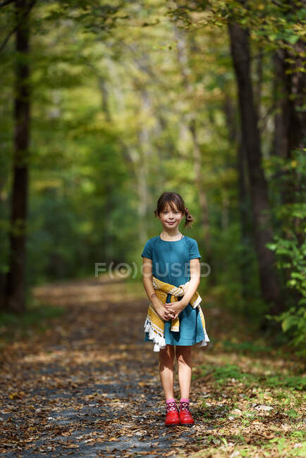 Chica sonriente de pie en un sendero en el bosque, Estados Unidos - foto de stock