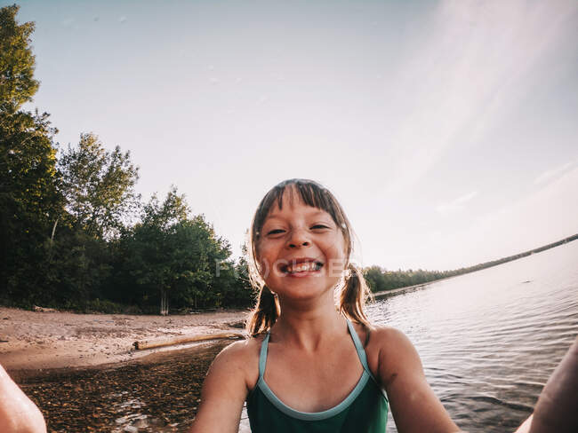 Retrato de una niña sonriente de pie junto a un lago, Lake Superior, Estados Unidos - foto de stock