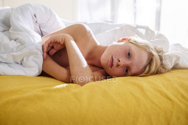 Хлопчик лежить у ліжку і прокидається. — стокове фото