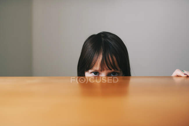 Girl hiding behind a table — Stock Photo