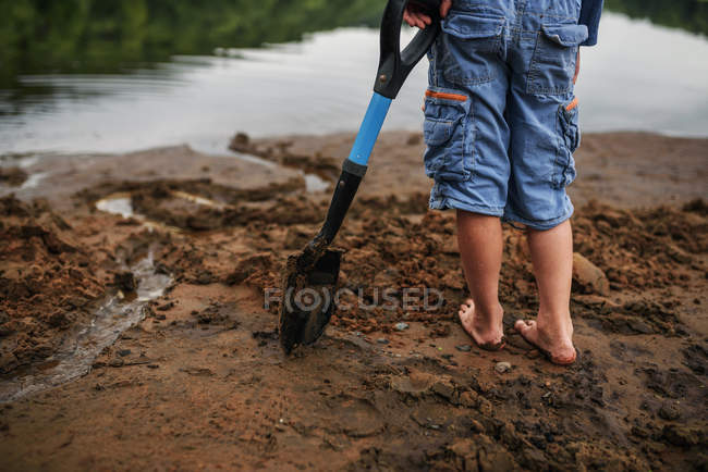 Хлопчик стоїть на пляжі тримає лопату — стокове фото