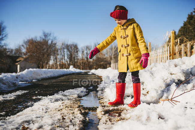 Ragazza in piedi vicino a una pozzanghera di neve che si scioglie, Stati Uniti — Foto stock
