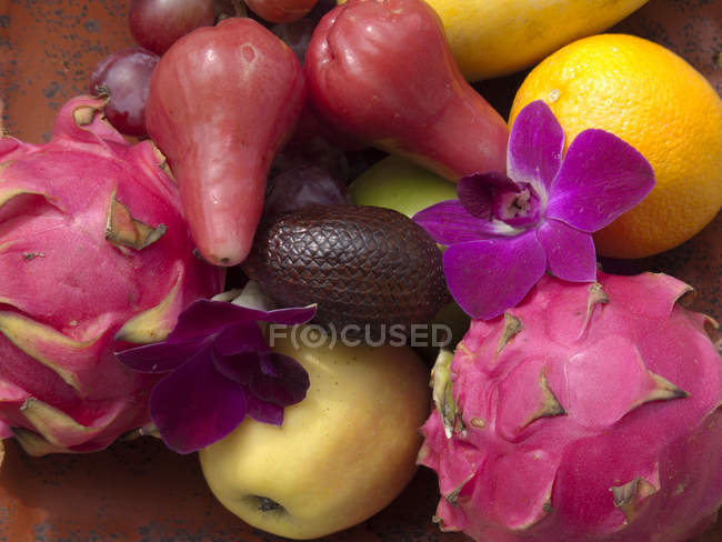 Tropical fruits and flower arrangement — Stock Photo