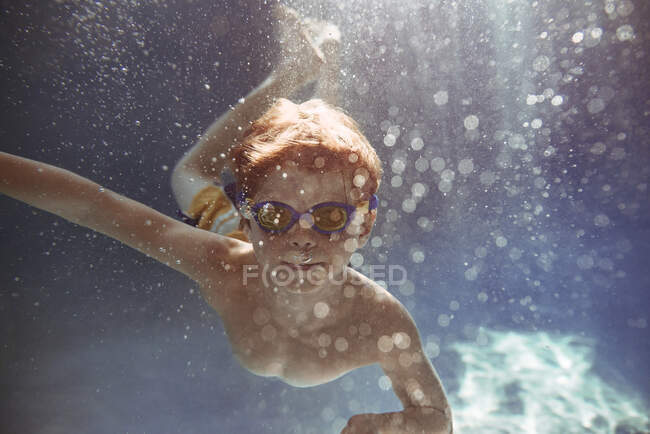 Nahaufnahme eines Jungen, der in einem Schwimmbad unter Wasser schwimmt — Stockfoto