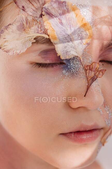 Retrato de belleza conceptual de una mujer con flores secas en la cara - foto de stock