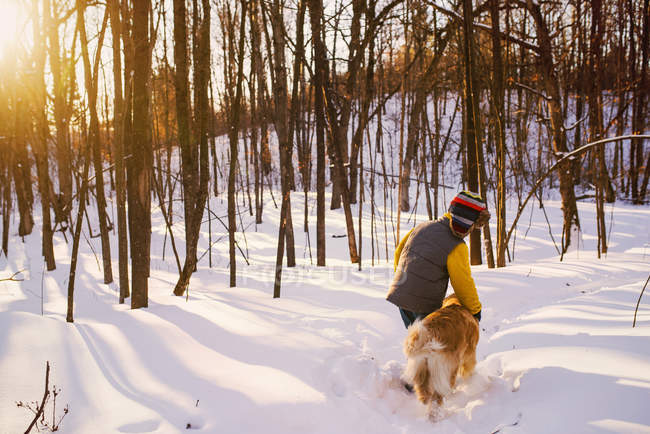 Ragazzo che cammina attraverso una foresta nella neve con il suo cane, Stati Uniti — Foto stock
