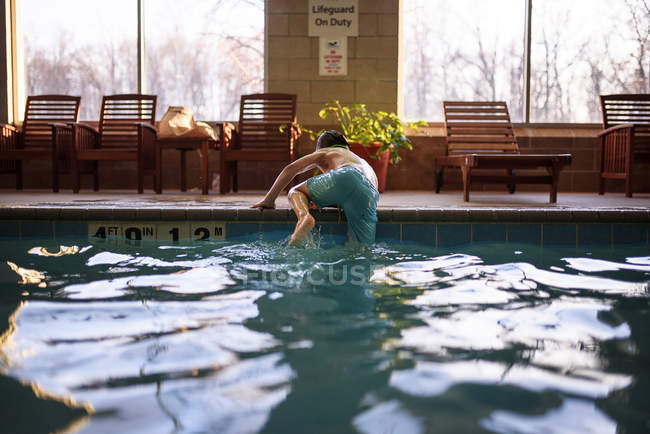 Boy climbing out of a swimming pool — Stock Photo