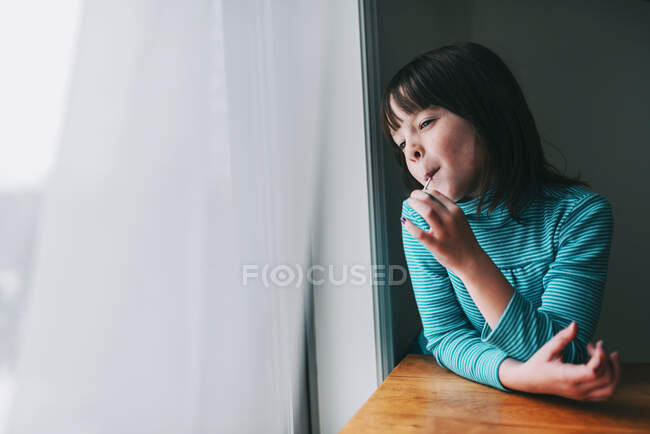 Retrato de una chica sonriente comiendo una piruleta - foto de stock