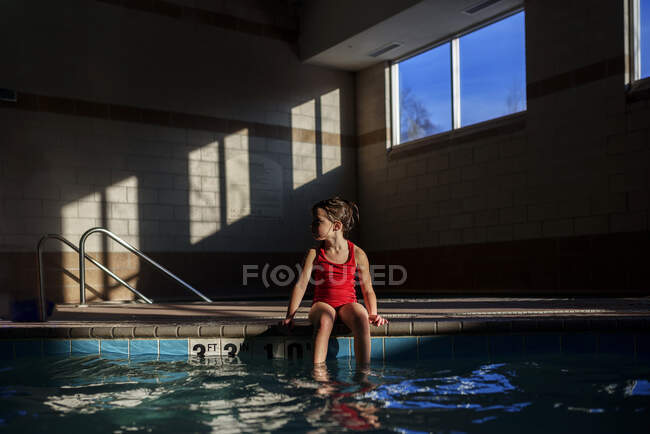 Mädchen sitzt am Rand eines Swimmingpools — Stockfoto
