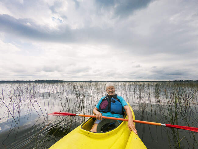 Smiling senior woman kayak on a lake, Estados Unidos - foto de stock