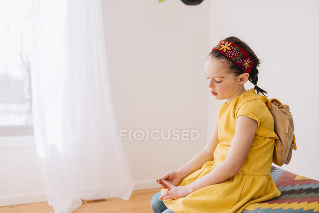 Mädchen sitzt auf einem Schemel und hält einen Zettel — Stockfoto