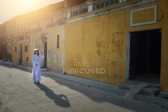 Donna che cammina per strada indossando abiti tradizionali, Hoi An, Vietnam — Foto stock