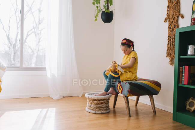 Дівчина сидить на табуреті, відкриваючи рюкзак — стокове фото