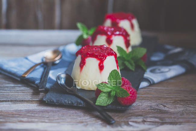 Three panna cotta desserts with raspberry coulis, raspberry and mint — Stock Photo