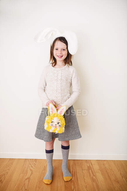 Porträt eines lächelnden Mädchens mit Hasenohren, das eine Hasentüte hält — Stockfoto