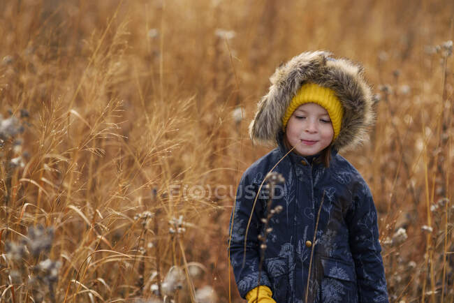 Ritratto di una ragazza sorridente in piedi in un campo che mastica un pezzo di erba lunga, Stati Uniti — Foto stock