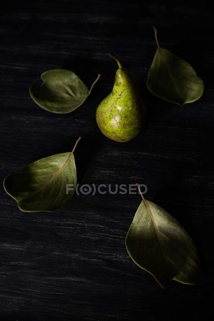Closeup view of Pear on a table surrounded by leaves — Stock Photo