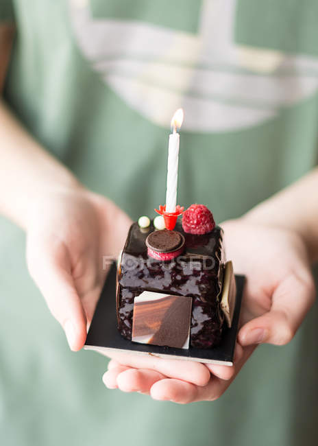 Primer plano de un niño sosteniendo un pastel de cumpleaños de sachertorte - foto de stock